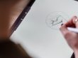 From above of crop anonymous artist with stylus in hand drawing creative sketch on graphics tablet